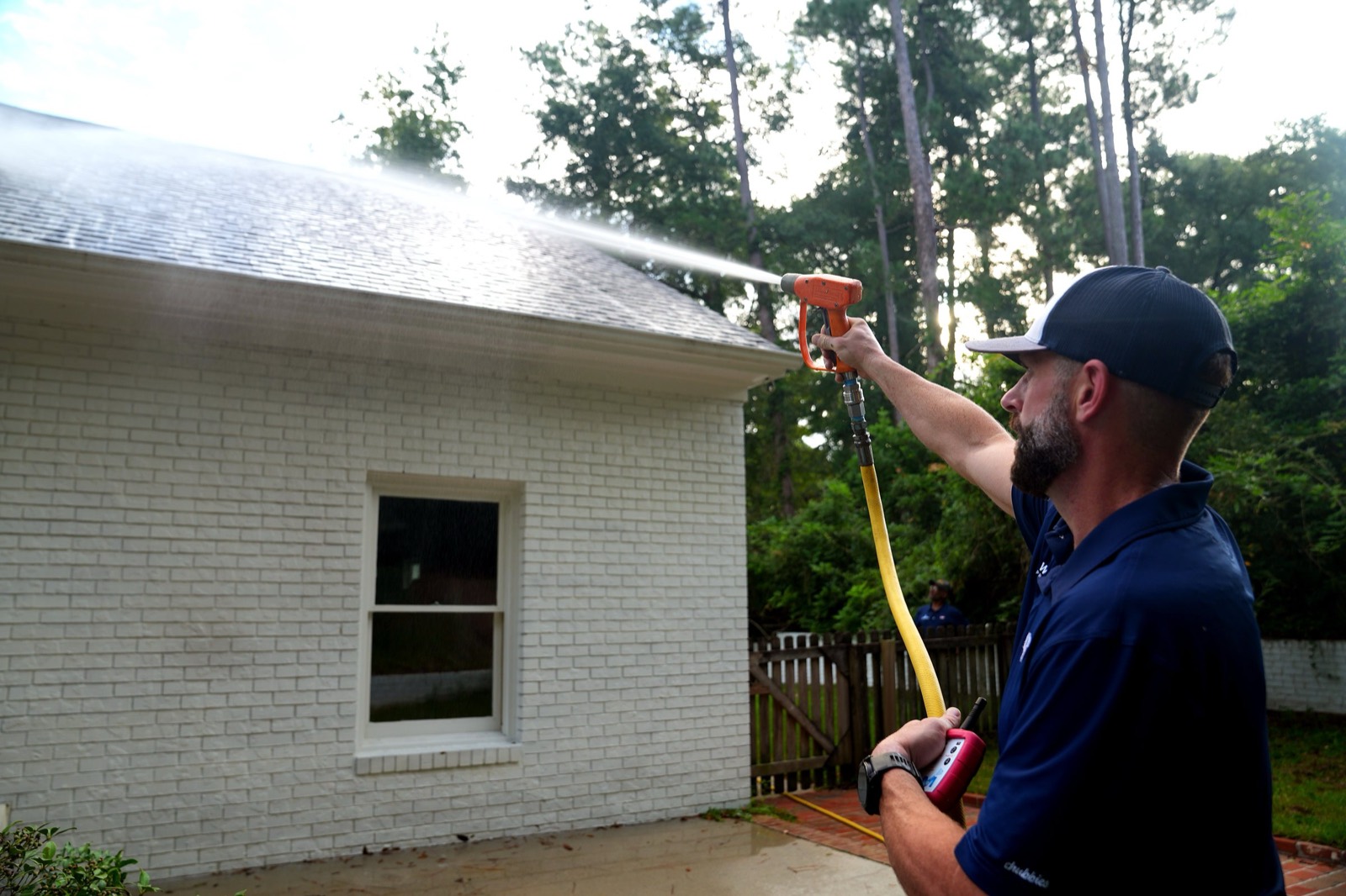 Cameron soft washing the roof and painted brick wall of a house from the ground