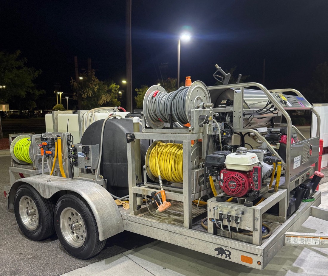 Trailer-mounted pressure washing rig with water tank, hose reels and engines
