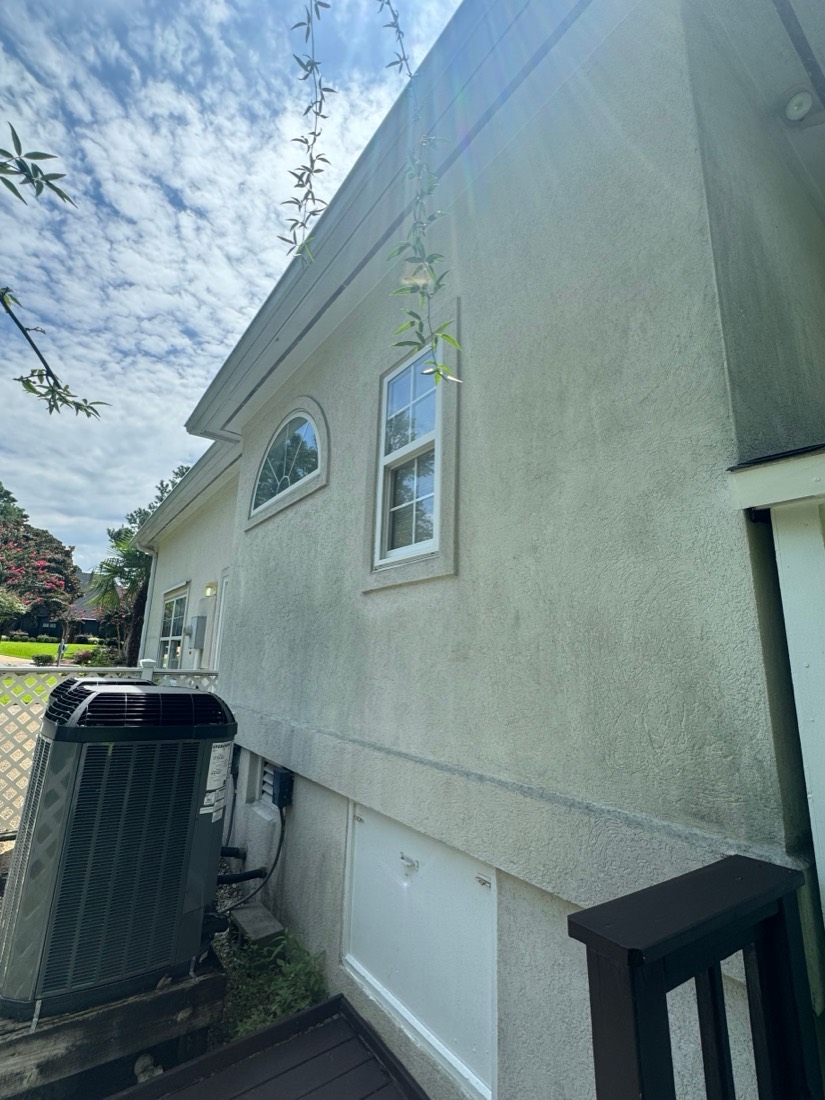 Stucco house wall with green streaks before a soft wash